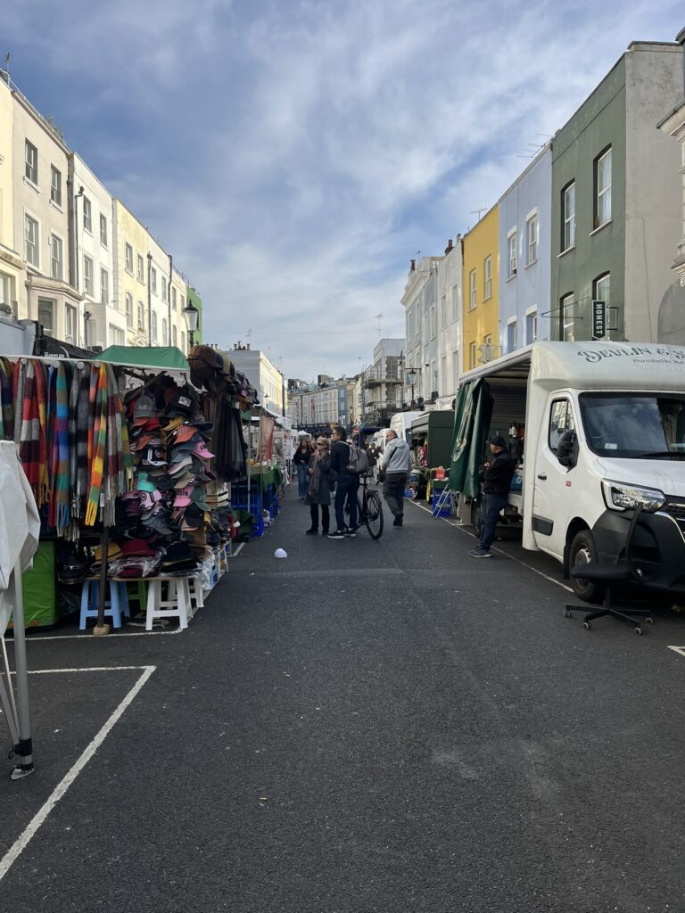 Portobello road market London, ulica so stánkami s rôznym tovarom.